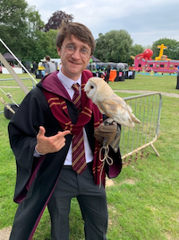A guest dressed
          as Harry Potter at an outdoor function holding a barn owl