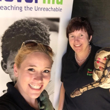 Kayleigh and Hazel standing in front of a large poster at a charity event