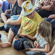 A parent and child holding a python across their laps